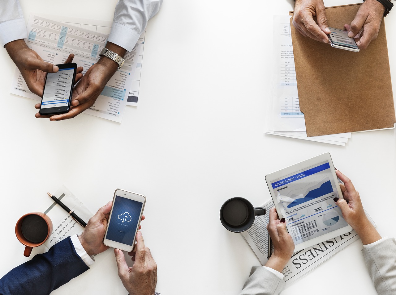 Four pair of hands holding tablets and cellphones